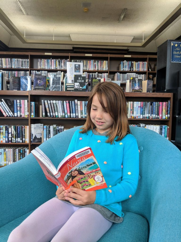 Erin's daughter reading a book at the library in Watertown, WI